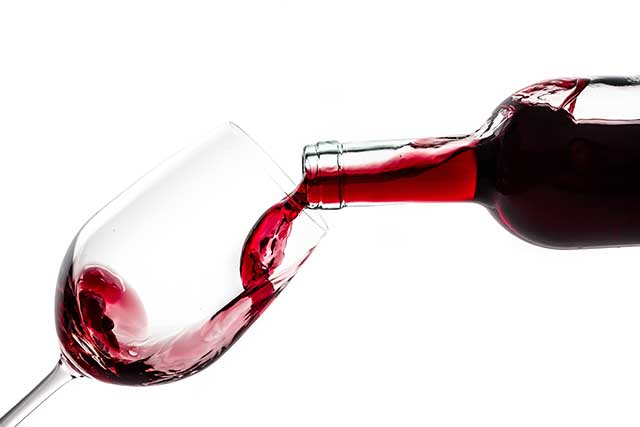 Pouring Red Wine From a Bottle Into a Glass.