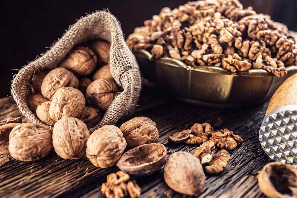 Shelled and Unshelled Walnuts On a Wooden Table.