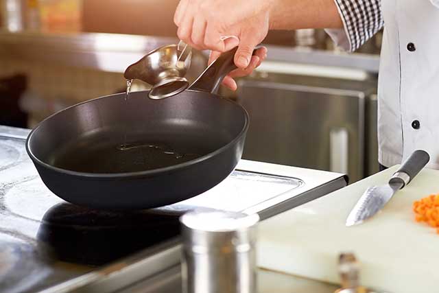 Chef Pouring Peanut Oil Into a Frying Pan.