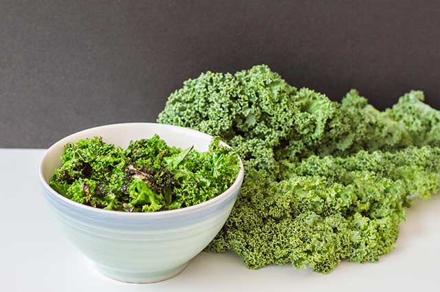 A Bowl of Kale Chips and Leaves of Fresh Kale.