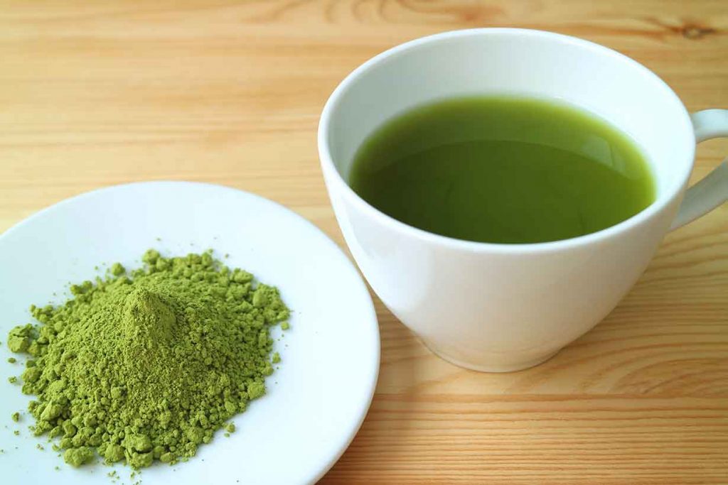 Cup of Matcha Tea Next To Matcha Powder.