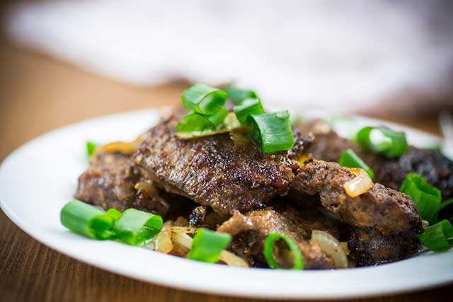 Fried Liver, Onions, and Green Onions On a Plate.