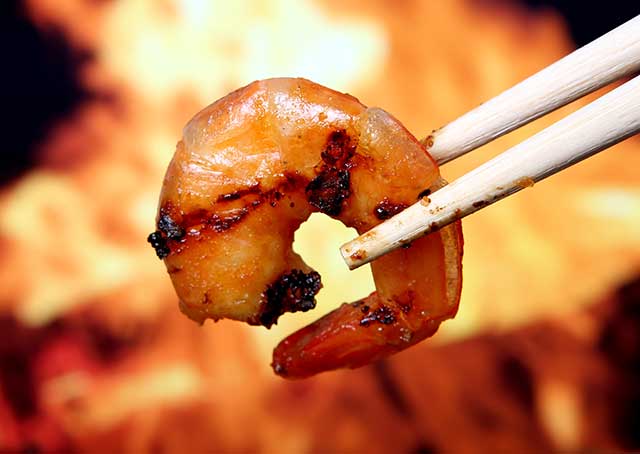 Holding King Tiger Prawn Shrimp With Wooden Chopsticks.