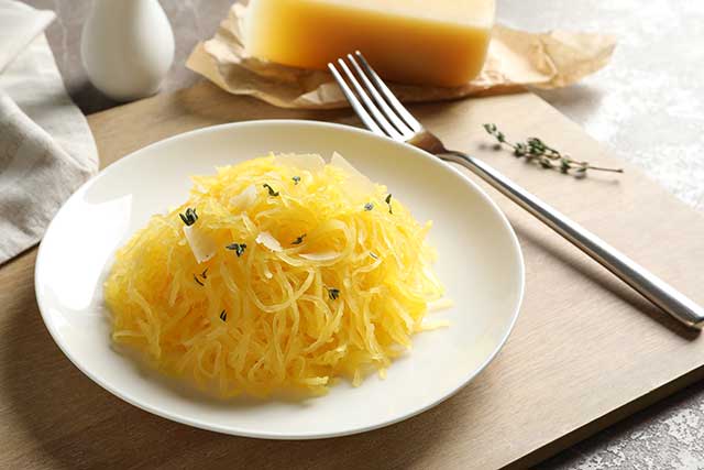 Plate Containing Cooked Spaghetti Squash Next To a Fork.