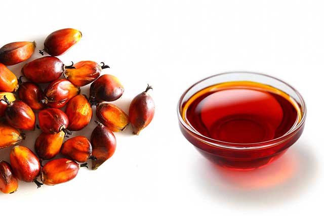 Red Palm Fruit Next To a Glass Bowl of Red Palm Oil.