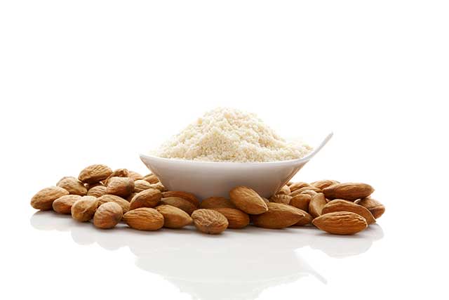 Bowl of Almond Flour Next To Pile of Whole Almond Nuts.