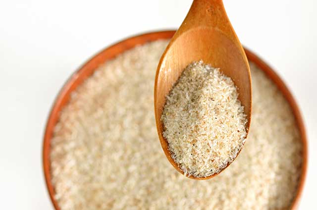 Ground Psyllium Husk In a Wooden Bowl and On Wooden Spoon.