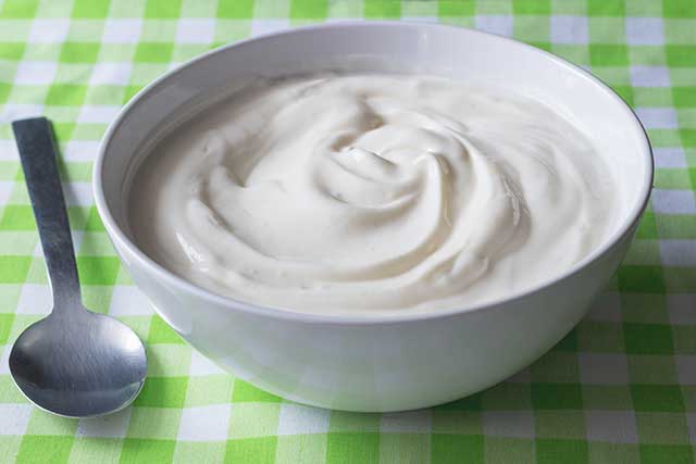Greek Yogurt In a White Bowl With a Metal Spoon.