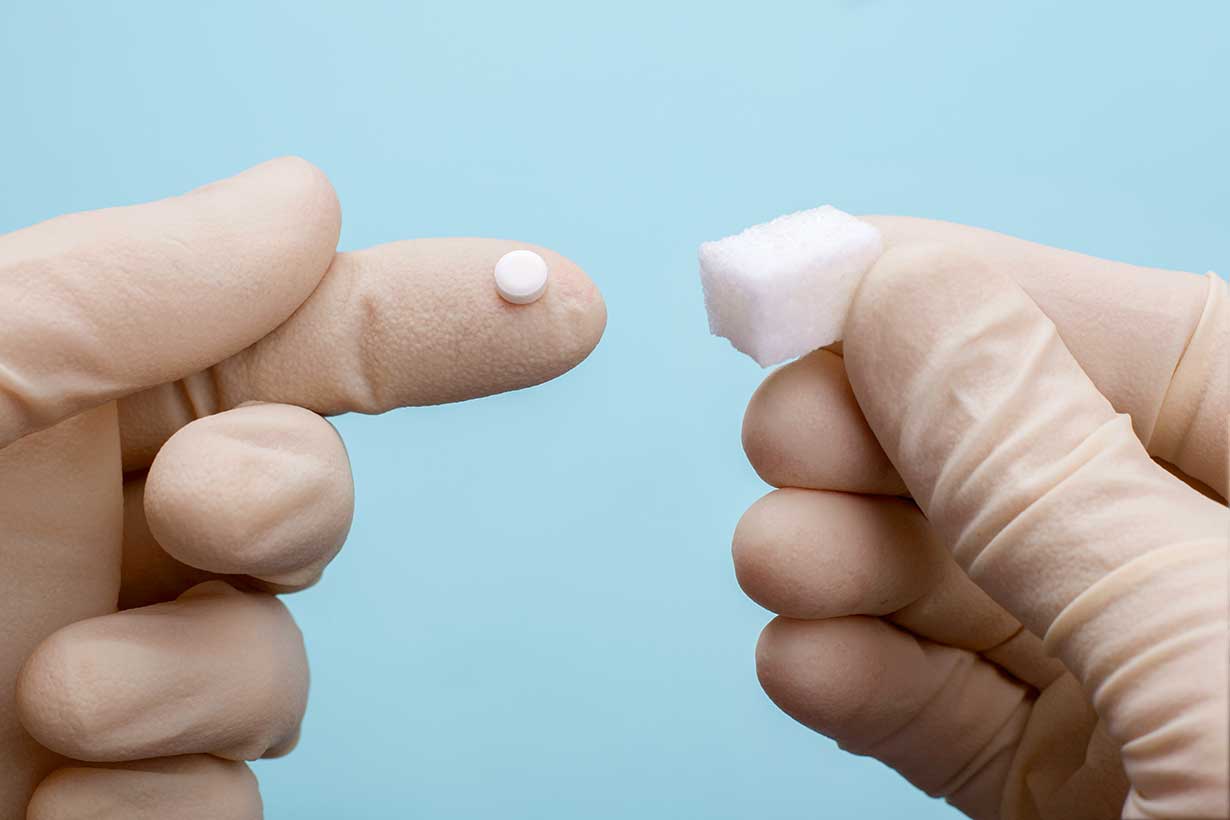 Sucralose Splenda Tablet and Sugar Cube In Different Hands.