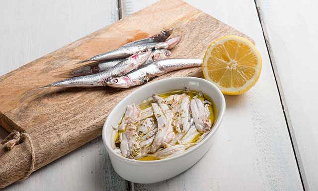 Whole Anchovies and Marinated Anchovy Fillets In White Bowl.