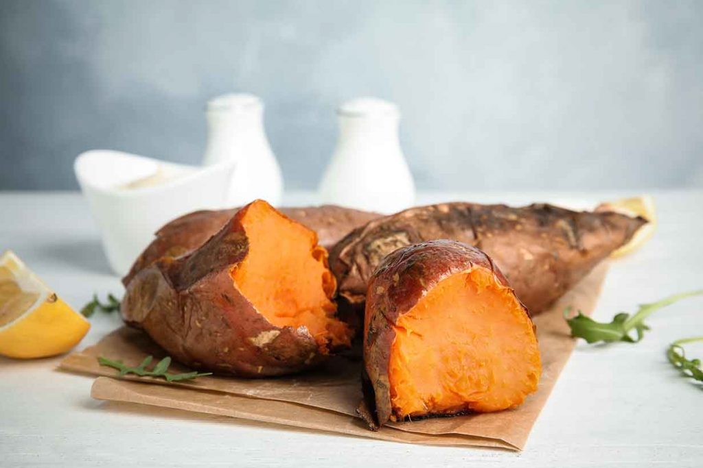 Baked Sweet Potato Cut In Half With Orange Flesh Showing.