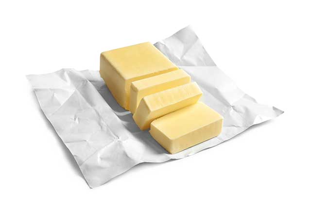 Block of Butter Cut Into Pieces On Top of Its Wrapping Foil.