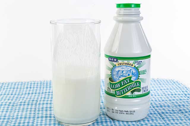 Low Fat Buttermilk In a Glass Next To Product Bottle.