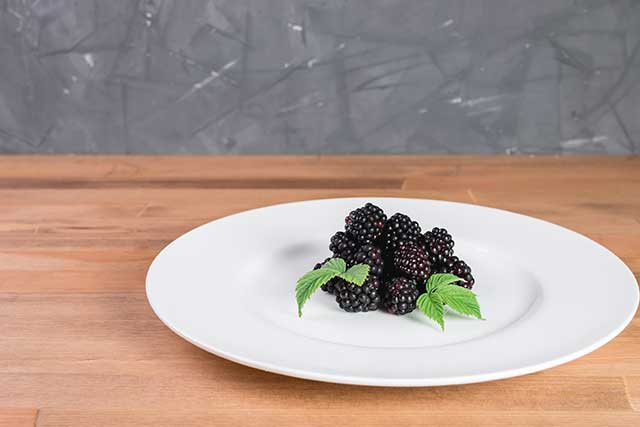 Pile of Boysenberries On a White Plate.