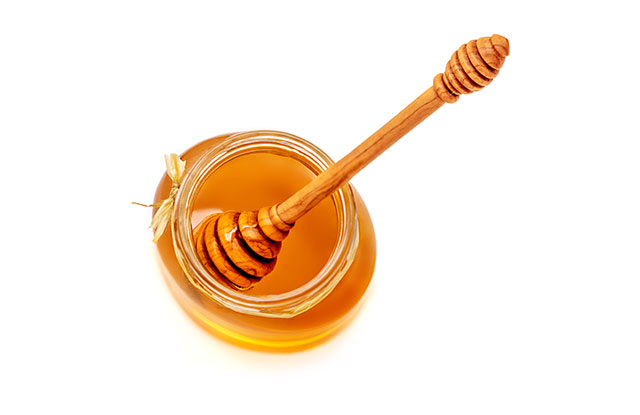 Honey Dipper In Jar of Sticky Honey.