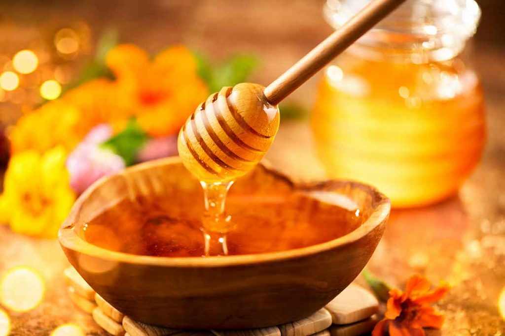 Thick and Sticky Honey In a Bowl With Honey Dipper.