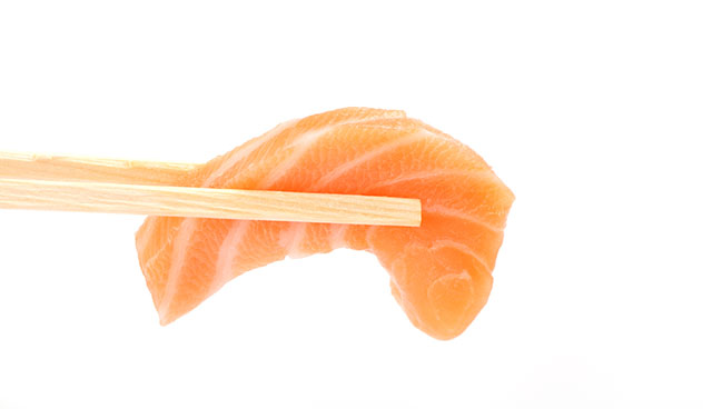  Un Morceau de Sashimi de Saumon Tenu Dans Deux Baguettes.