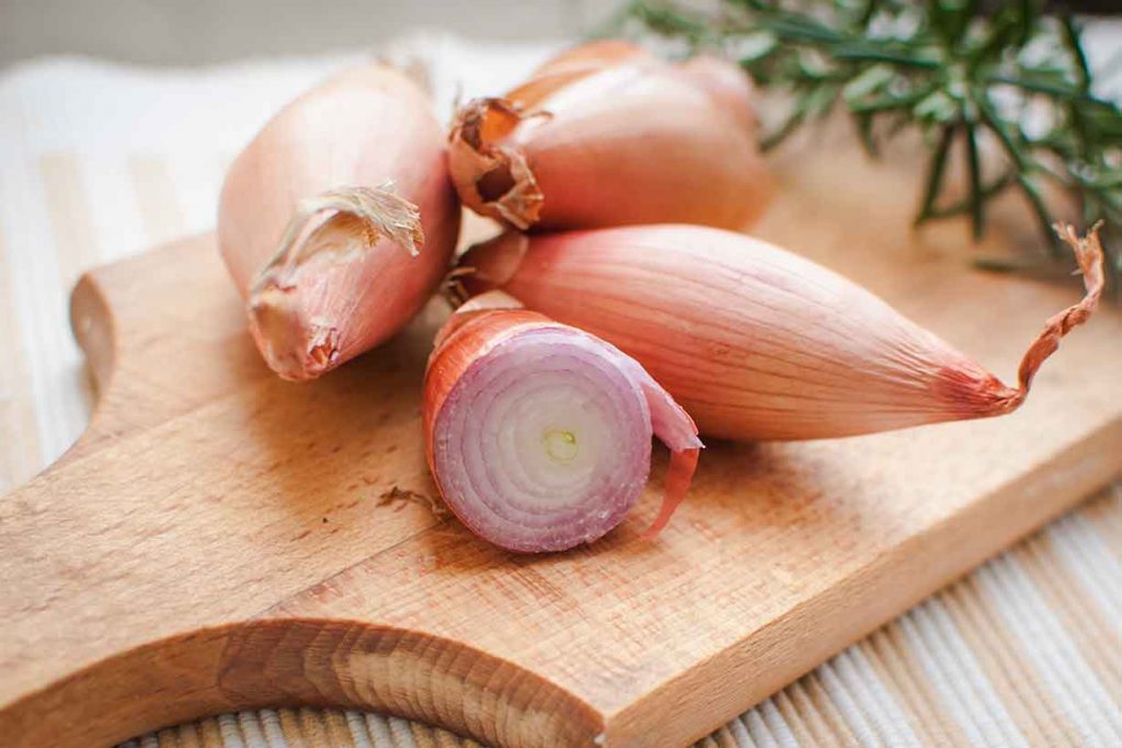 Four Shallots on a Wooden Chopping Board.