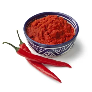 Moroccan harissa paste in a bowl next to chili peppers.