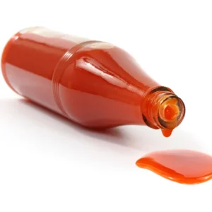 A bottle of hot sauce on its side leaking.