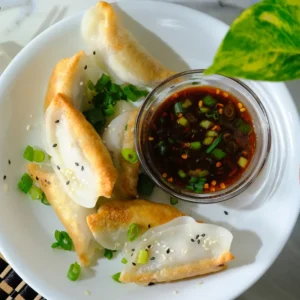 Fried dumplings served with a small glass bowl of ponzu sauce as a dip.