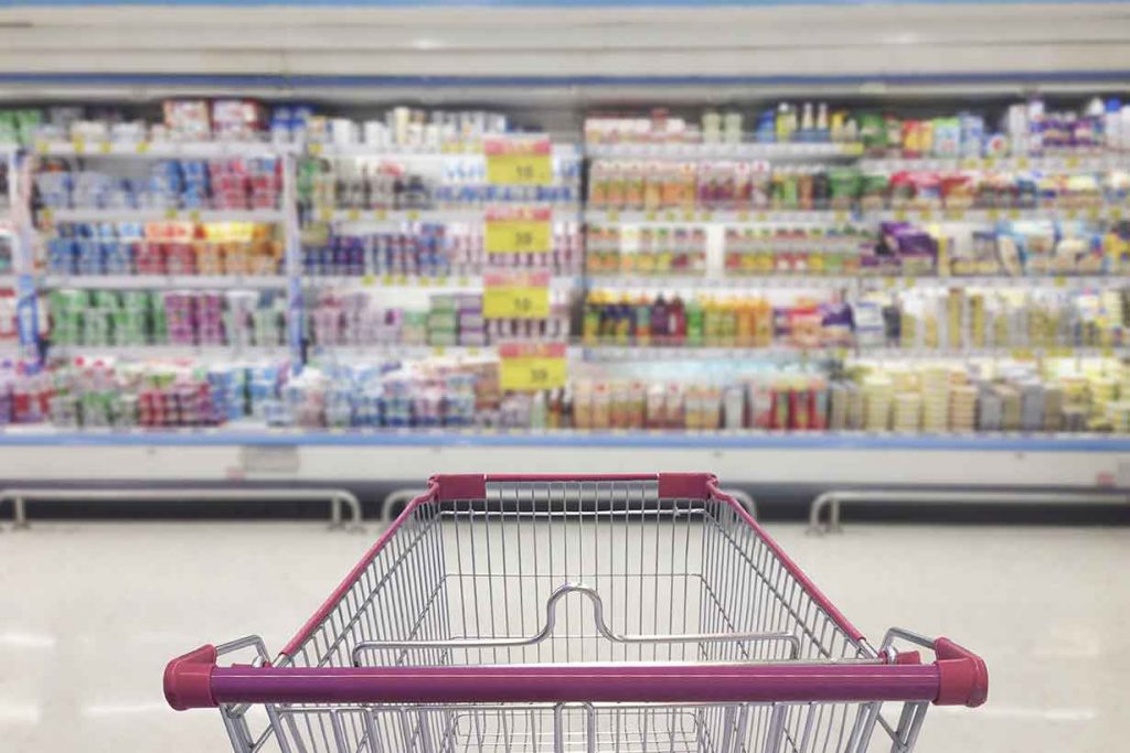 A Trolley In Front of Processed Foods In a Supermarket.