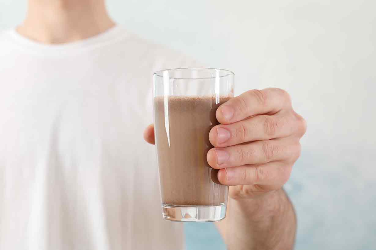 Person Holding a Glass of Chocolate Milk.