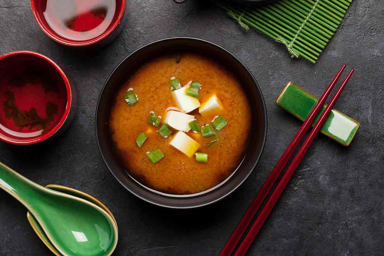 Traditional Miso Soup In a Bowl With Spoon and Chopsticks.