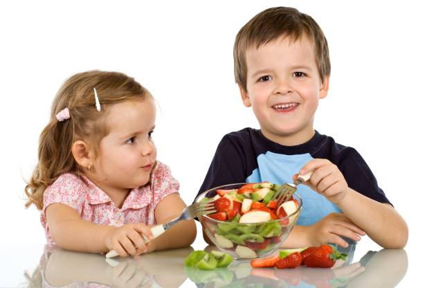 Boy and Girl Eating Fruit From a Fruit Bowl.