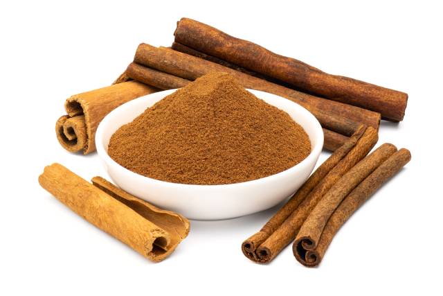 Ground Cinnamon and Cinnamon Bark Alongside Each Other.