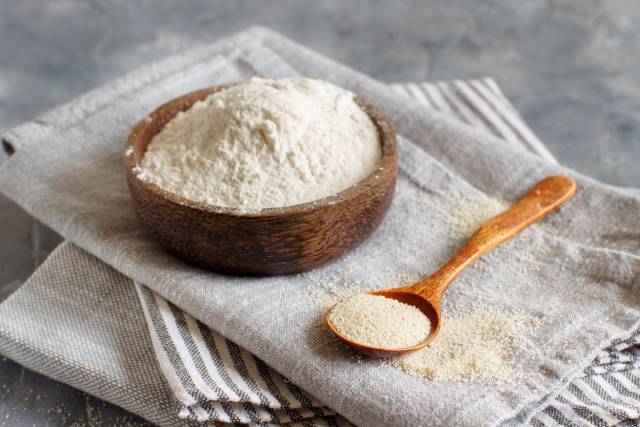 Fonio Flour and Fonio Seeds In a Bowl and Spoon Respectively.