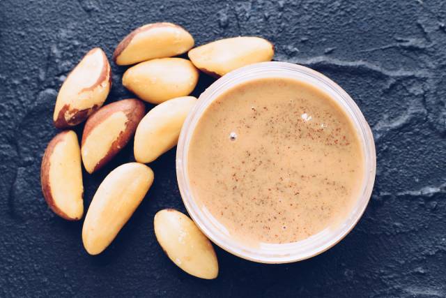 Brazil Nut Butter In a Jar Next To Whole Brazil Nuts.