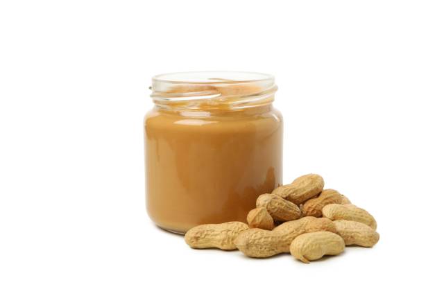 A Jar of Smooth Peanut Butter Next To Whole Peanuts.