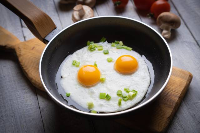 Two fried eggs in a black pan.