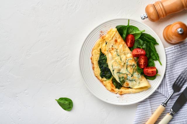 An omelet served with spinach and cherry tomatoes.