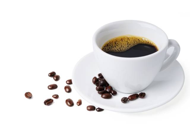 White cup full of black coffee on a white saucer.