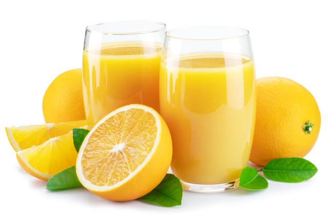 Whole and Half Oranges Next To Two Glasses of Fruit Juice.