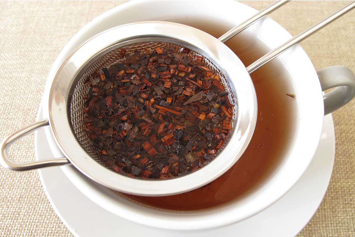 A Cup of Honeybush Tea With Loose Leaves In a Tea Infuser.