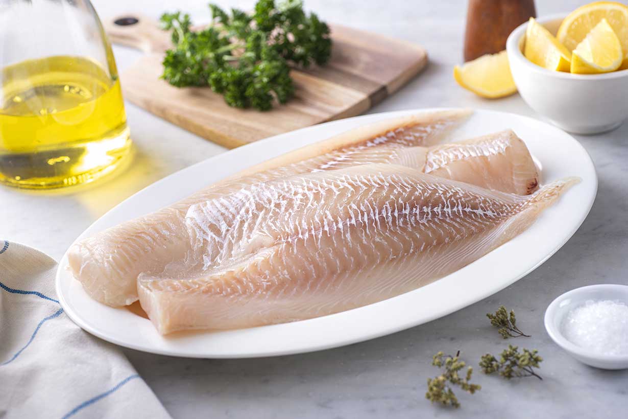 Several Haddock Fillets On a White Plate.