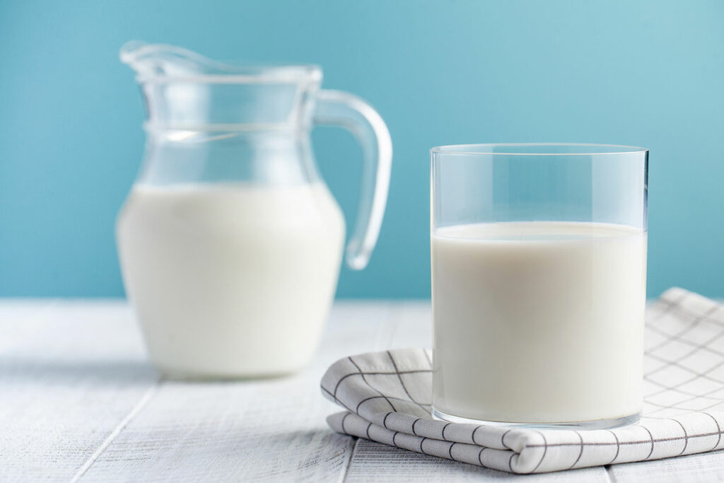 A Jug of Milk Next To a Glass of Milk.