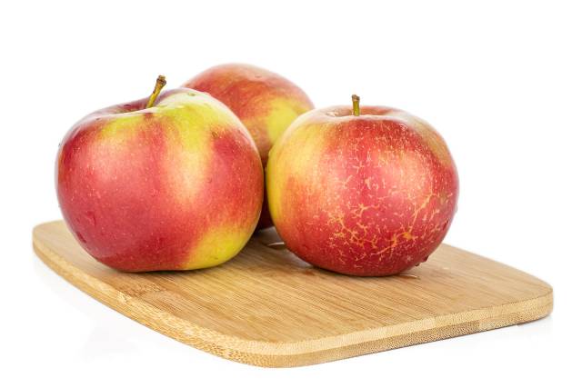 Three Jonagold Apples On a Wooden Board.