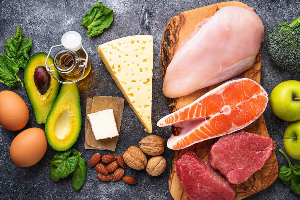 Various Foods Suited For a Low-Carb Diet (Avocado, Eggs, Fish, Meat, Nuts, Green Vegetables).