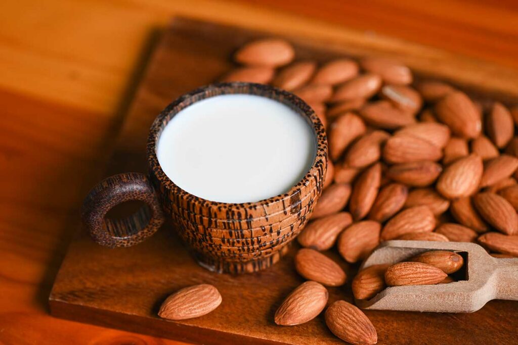 A Cup of Almond Milk Next To Almonds.