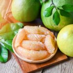 Whole Pomelo Fruit In Peel Next To Unpeeled Pomelo Slices.