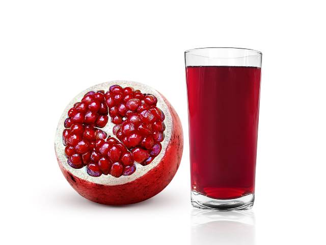 Glass of Pomegranate Juice Next To Pomegranate Fruit.