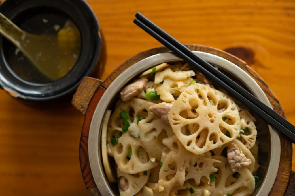 A dish in a pot containing lotus root slices, with chopsticks.