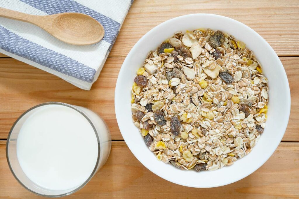 A bowl of muesli next to a glass of milk.