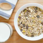 A bowl of muesli next to a glass of milk.