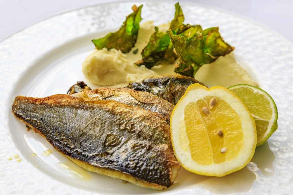 A grilled fillet of Branzino (European Sea Bass) on a plate with vegetables.