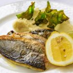 A grilled fillet of Branzino (European Sea Bass) on a plate with vegetables.